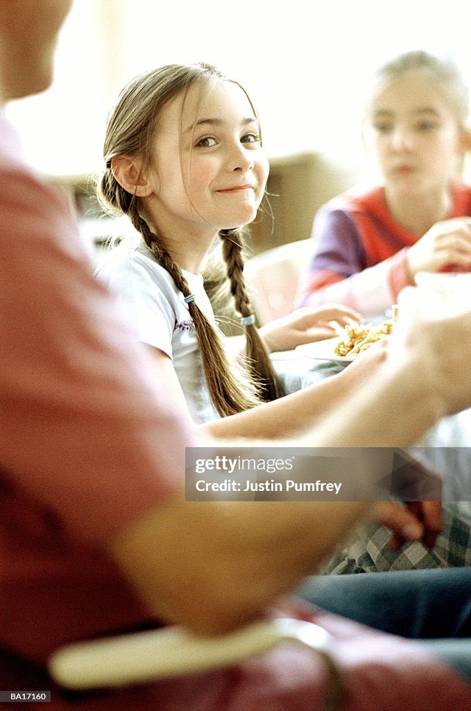 Girl (8-10) at dinner table with family, portrait
