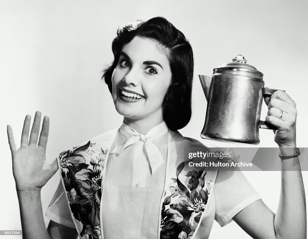 Young woman holding kettle, smiling, portrait (B&W)