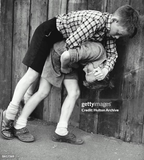 Two boys fighting by fence in street