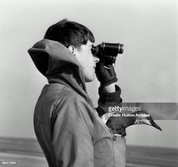 Boy with bird in pocket looking through binoculars