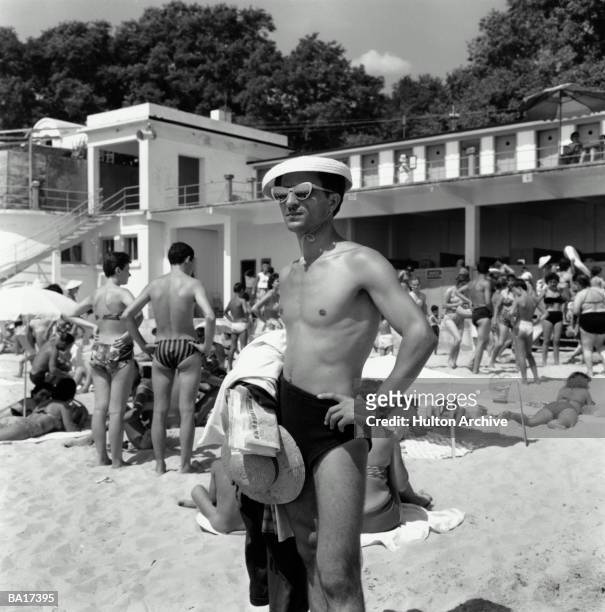 Man wearing cap and sunglasses posing on beach