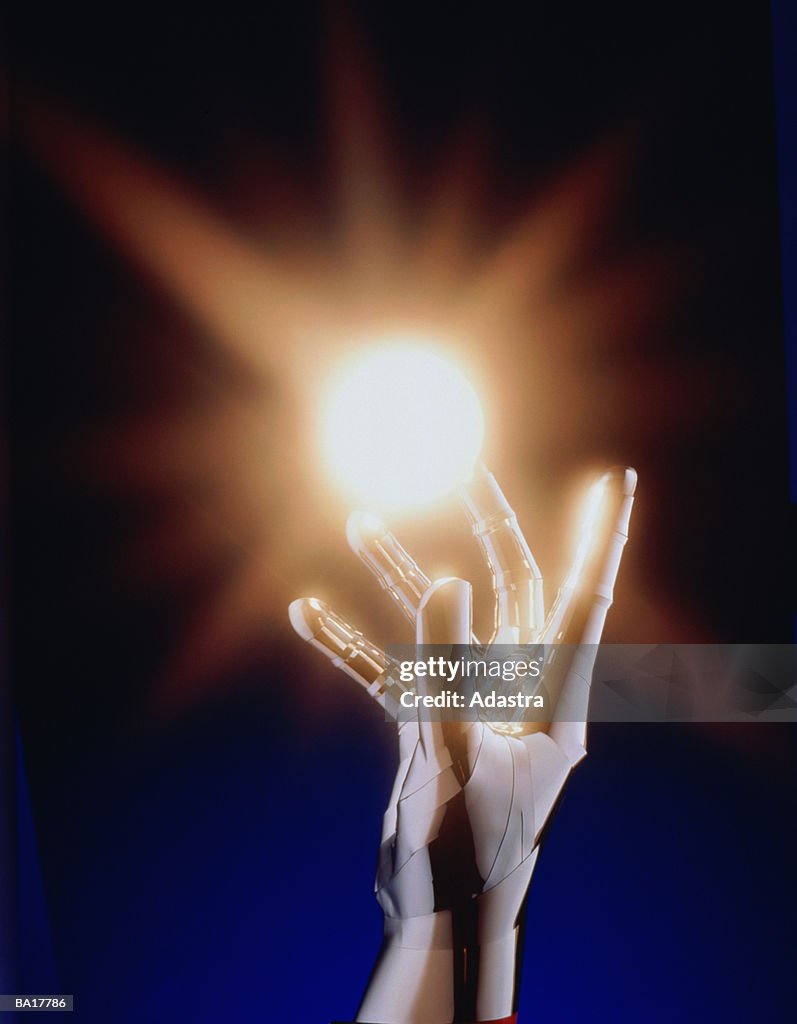 METALLIC HAND REACHING UP TO BALL OF LIGHT