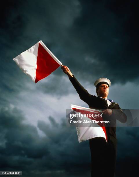 sailor in naval uniform using semaphore, against stormy sky - semaphore 個照片及圖片檔