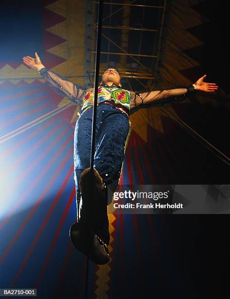 tightrope walker on wire in big top, arms outstretched, low angle - tightrope walker stock pictures, royalty-free photos & images