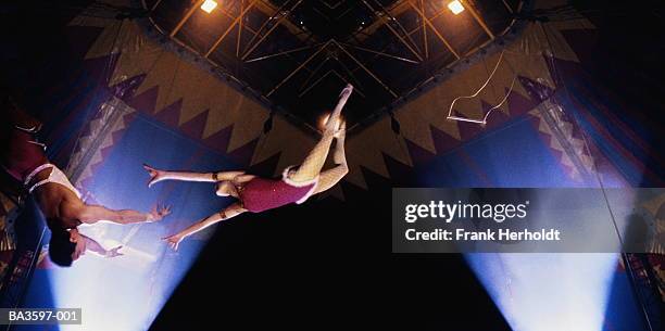 circus trapeze act, woman in mid-leap,low angle view (composite) - trapeze stock-fotos und bilder