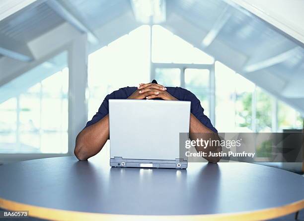 man with hands on back of head behind laptop computer - justin stock pictures, royalty-free photos & images