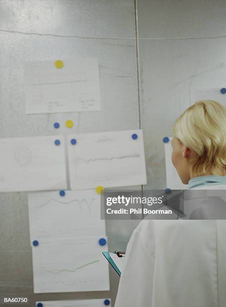 female technician looking at graphs on wall, rear view - phil stock pictures, royalty-free photos & images