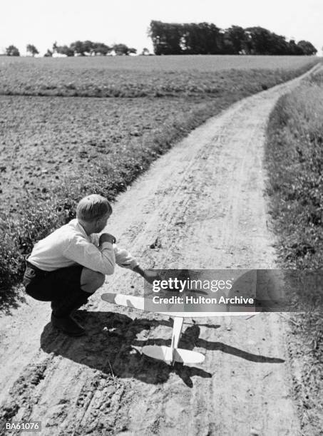 Full-length image of a boy crouching on a dirt pat