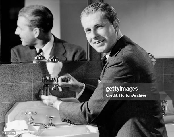 Man wearing a suit grins as he uses a soap dispe