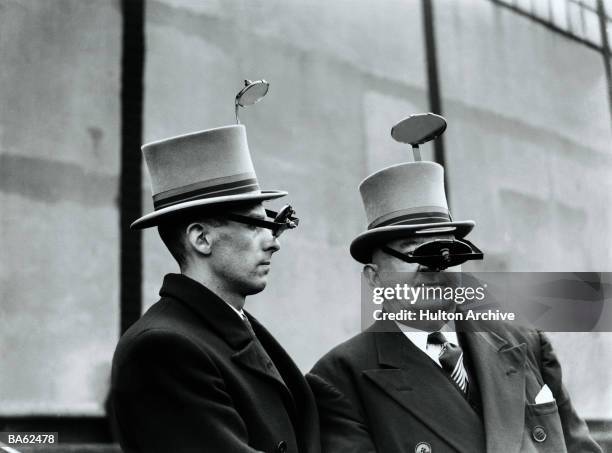 Two men try out new periscope hats at the British Industries Fair at White City, west London. The hats, designed by a Mr Battersby, are intended to...