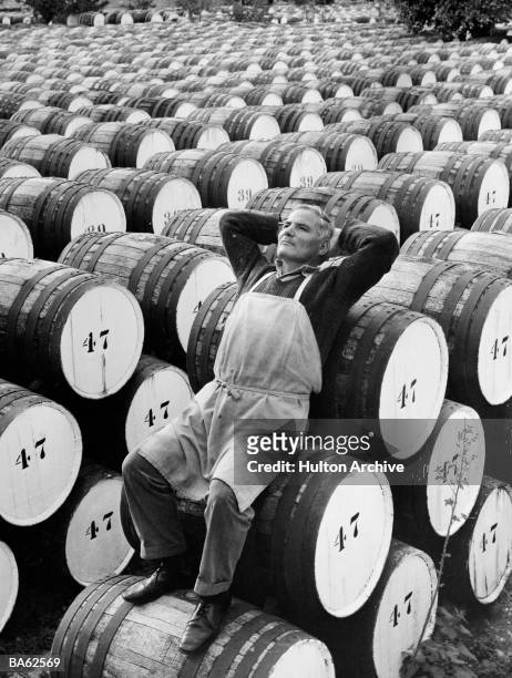 Cypriot man rests againsts a row of sherry barrels in an extensive outdoor barrel store at Limassol, Cyprus.