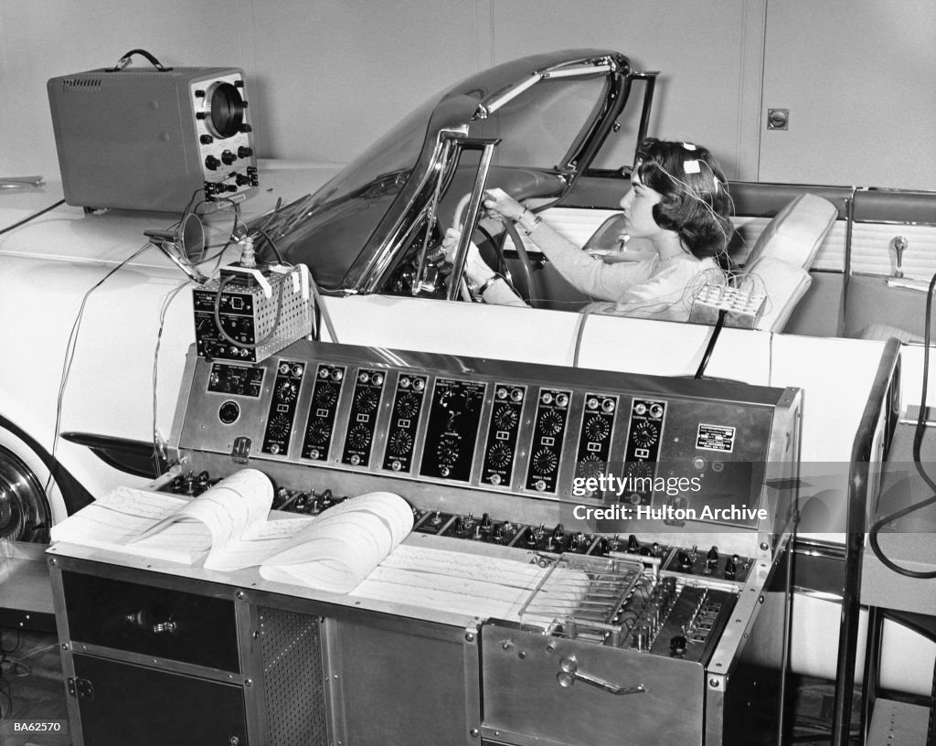 Woman with wires attached to head in driving simulation (B&W)