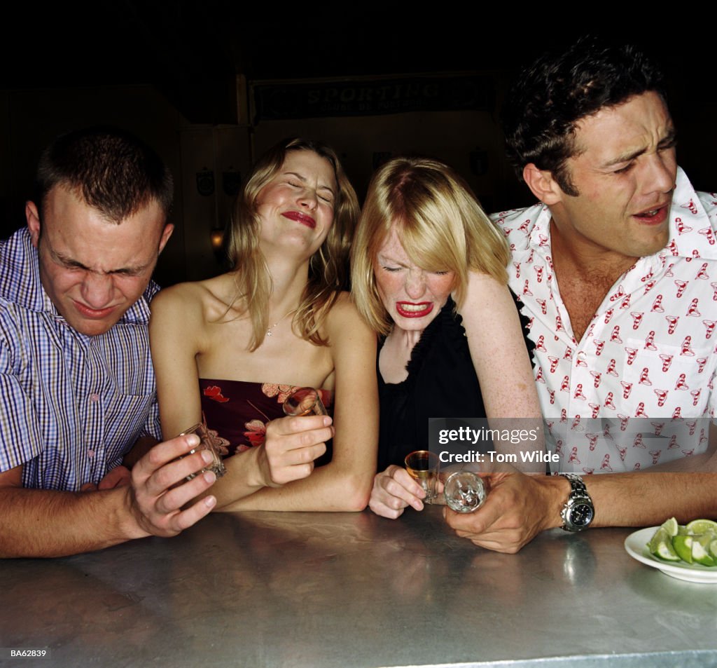 Four young friends drinking tequilla shots