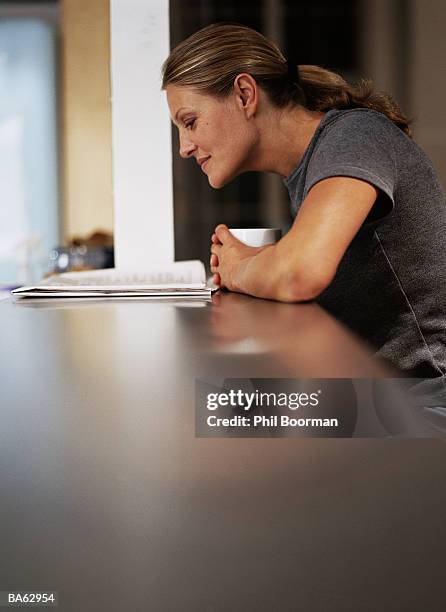 woman reading newspaper at table, profile - phil stock pictures, royalty-free photos & images