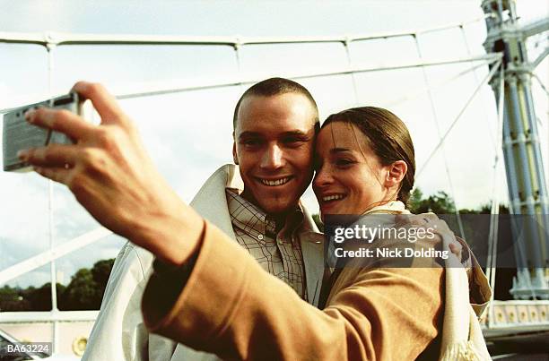 young couple on bridge taking photograph of themselves - albert foto e immagini stock