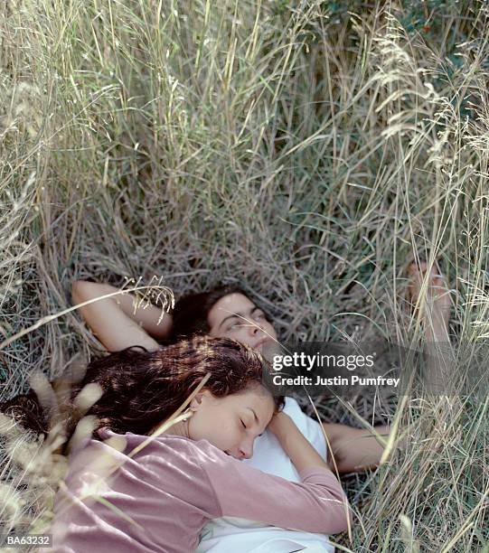 young couple on grass, woman asleep on man's chest, close-up - justin stock pictures, royalty-free photos & images