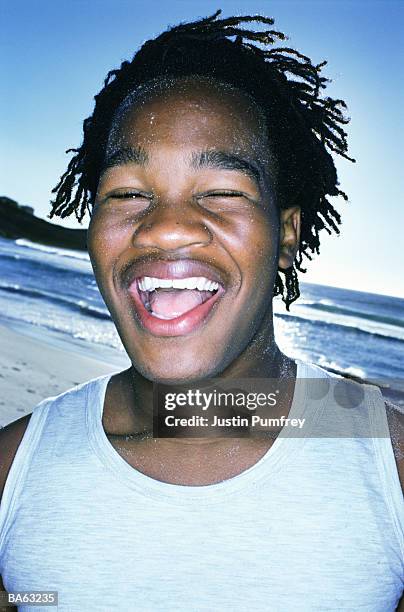 teenage boy (15-17) on beach laughing, portrait, close-up - hemden stockfoto's en -beelden