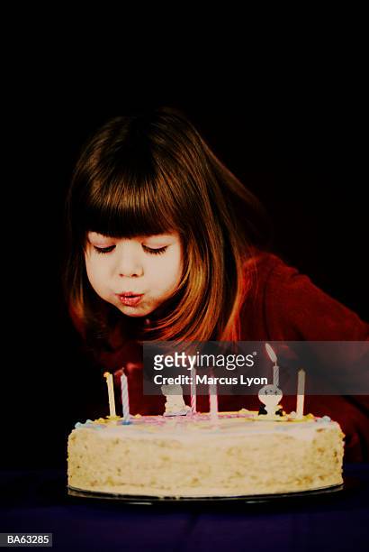 girl (5-7) blowing out candles on birthday cake - marcas stock-fotos und bilder