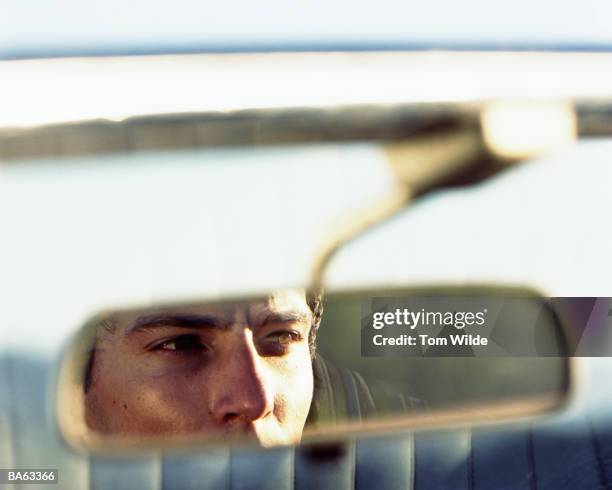 young man driving car, view through rear view mirror - désir photos et images de collection