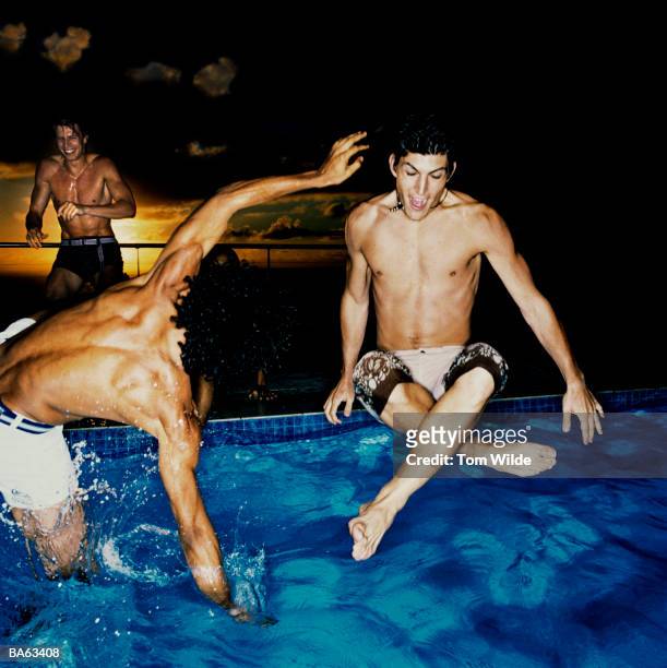 three young men jumping into swimming pool, smiling, sunset - swimming pool night stock pictures, royalty-free photos & images