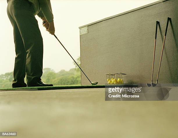 male golfer lining up stroke on practice range, low section - microzoa stock pictures, royalty-free photos & images