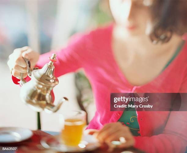 young woman pouring glass of tea (focus on teapot) - crosby imagens e fotografias de stock