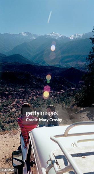 young couple leaning on 4x4, overlooking valley - crosby imagens e fotografias de stock