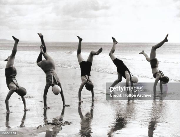 Group of people doing handstands on beach at Teignmouth, Devon, England, 1938.