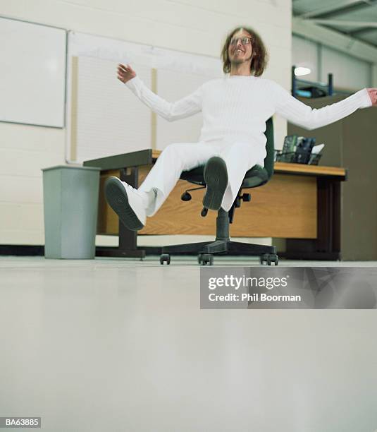 man sliding across floor on office chair (blurred motion) - phil stock pictures, royalty-free photos & images