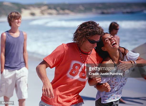 young couple playing on beach - justin stock pictures, royalty-free photos & images