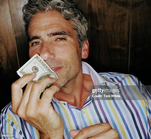 mature man holding a hundred dollar bill to mouth, portrait - vice stock-fotos und bilder