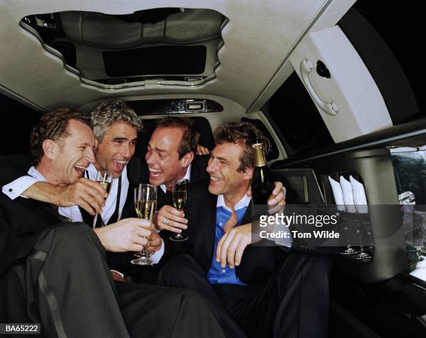 four mature men drinking champagne in back of limousine, laughing - 男性告別單身派對 個照片及圖片檔
