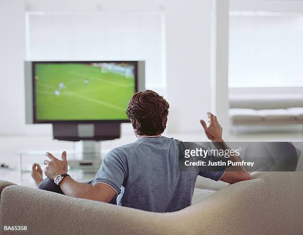 man watching football on television, rear view - watching stock-fotos und bilder