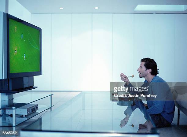 man watching football on television, eating tv dinner - mancave stockfoto's en -beelden