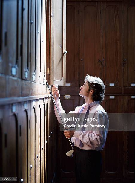 man taking golf club and ball from wooden locker - sports equipment locker stock pictures, royalty-free photos & images