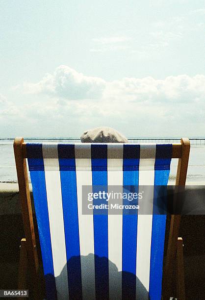 man in deckchair wearing flat cap, on promenade, rear view - microzoa stock pictures, royalty-free photos & images