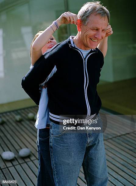 girl (12-14) sticking tongue out and pulling fathers ears, outdoors - dan kenyon bildbanksfoton och bilder