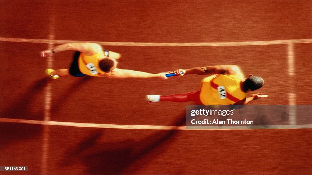 Athletes passing baton in relay  race, overhead, (Digital Composite)