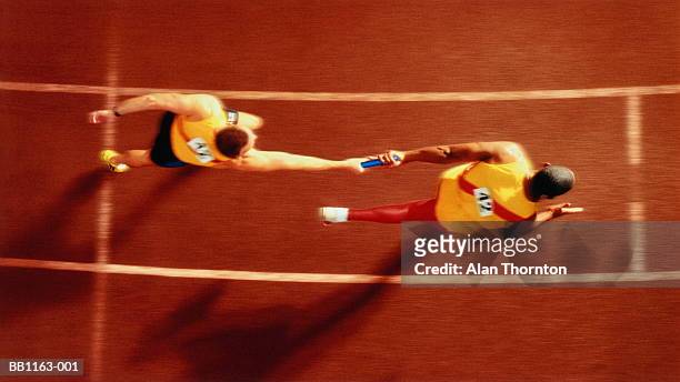 athletes passing baton in relay  race, overhead, (digital composite) - passing imagens e fotografias de stock