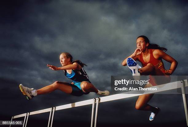 female athletes clearing hurdles, (colour enhanced) - hurdling track event fotografías e imágenes de stock