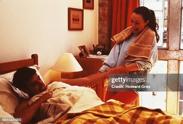 young couple,woman trying to drag man out of bed - woman sleep bedroom foto e immagini stock