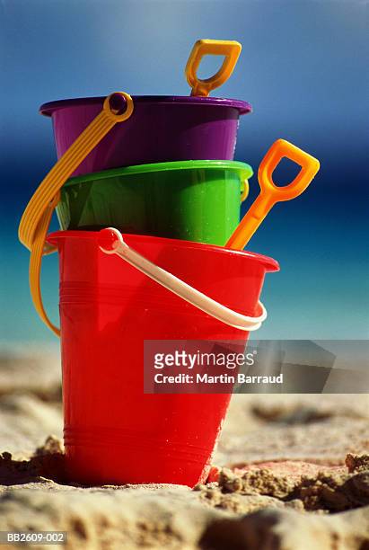 colourful child's plastic buckets and spades on beach - bucket and spade stock pictures, royalty-free photos & images