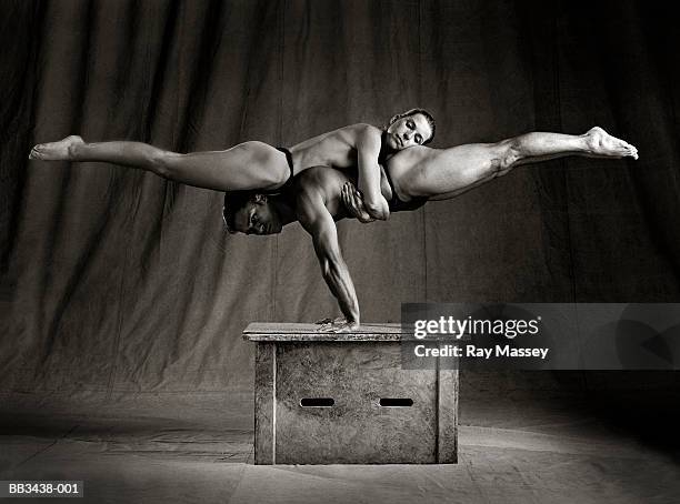 acrobats,woman supported by man balancing on hands (sepia tone) - akrobatik stock-fotos und bilder