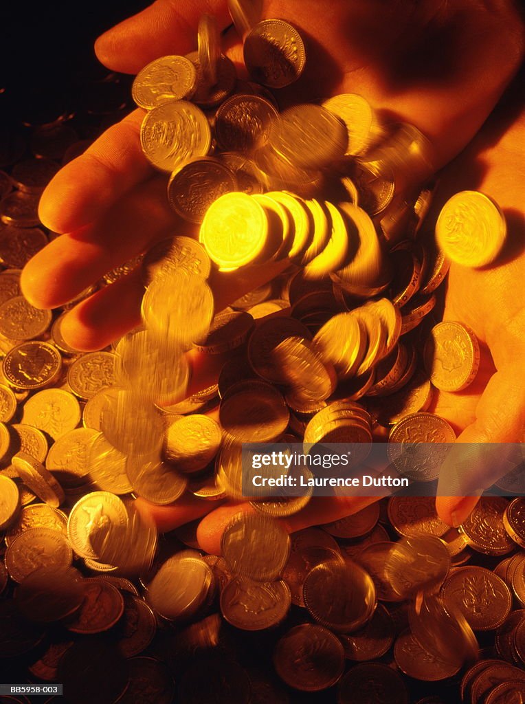 United Kingdom currency, man's hands filled with one pound coins