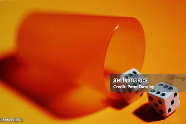 two dice showing sixes lying beside orange shaker - odds stock-fotos und bilder