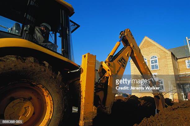 mechanical digger on construction site, england - earth mover stock-fotos und bilder