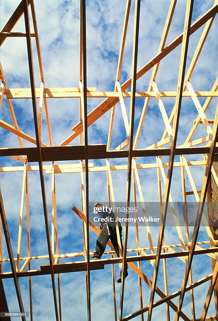 Construction worker amongst beams of roof, ground view