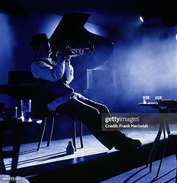 trumpet player performing in empty club (toned b&w) - pianist stockfoto's en -beelden