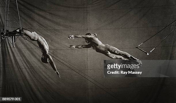 two circus trapeze artists in action (toned b&w) - trust stock pictures, royalty-free photos & images
