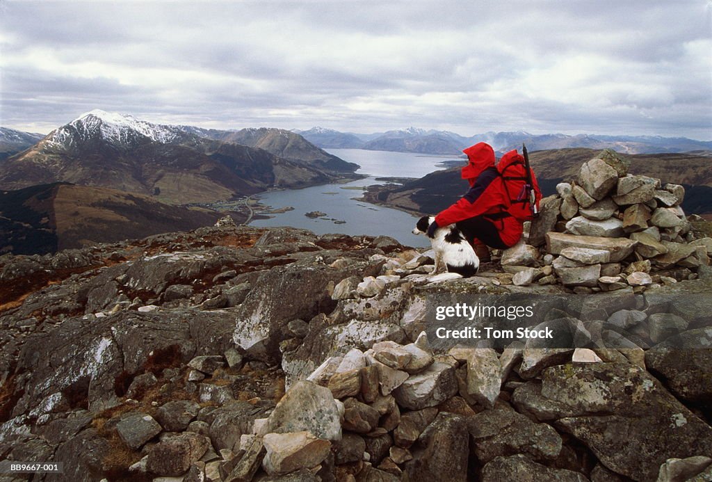 Female hiker and dog sitting on cairn,Loch Leven,Highland,Scotland